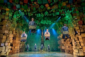 Cast members from Matilda The Musical on four swings over the stage at the Cambridge Theatre