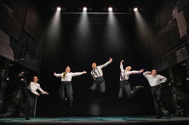 The cast of Operation Mincemeat facing the audience and jumping for joy