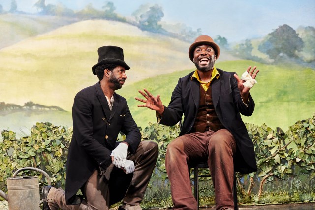 Tambo and Bones sit on a wall in the countryside in period dress