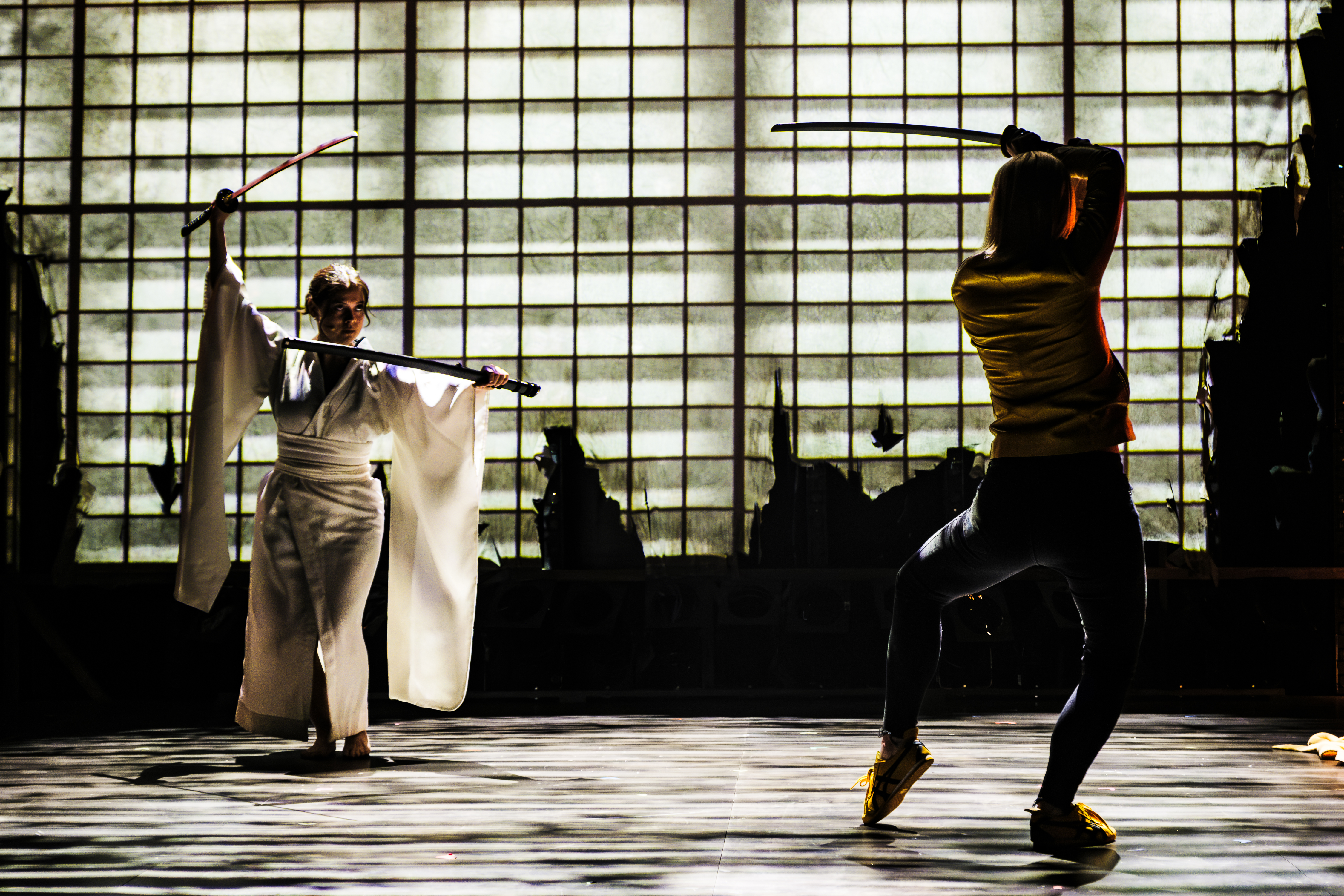 A scene from Tarantino Live with two women holding swords and circling each other, inspired by the film Kill Bill