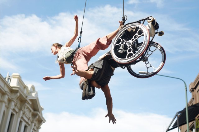 Acrobats dangle in the air with one sat in a wheelchair