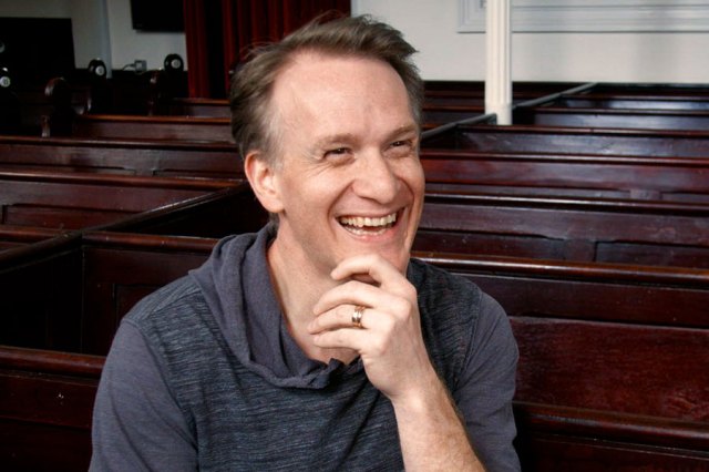 A photo showing Jamie Parker smiling, sitting in a pew