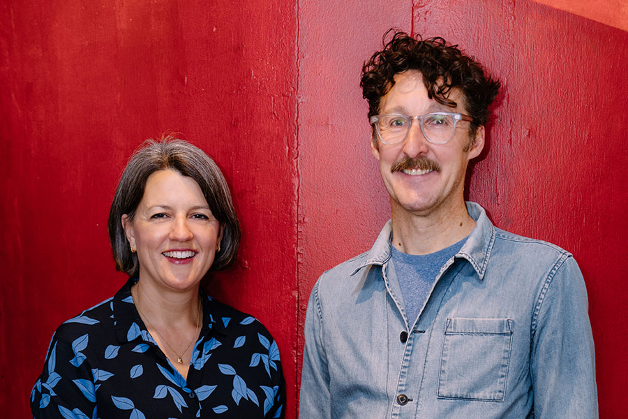 Henny Finch and Timothy Sheader stand in front of a red background