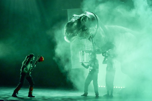 A scene from Dinosaur World Live featuring a Tyrannosaurus Rex puppet and a handler