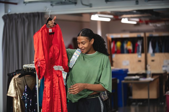 Actor Ivano Turco holding up a red dress in rehearsals for the Everybody's Talking About Jamie tour