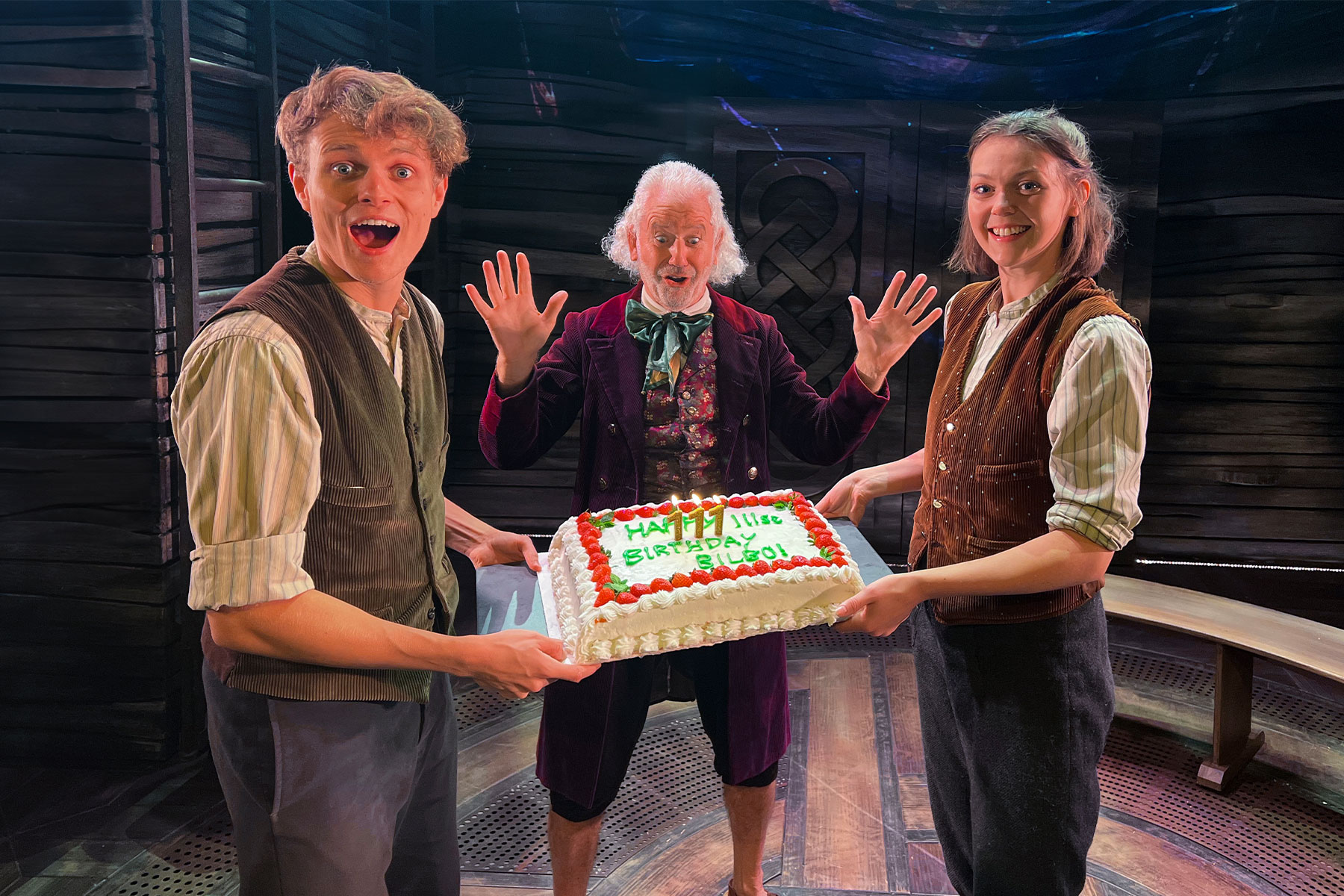 The Lord of the Rings cast members Geraint Downing, John O’Mahony and Amelia Gabriel on stage with a birthday cake