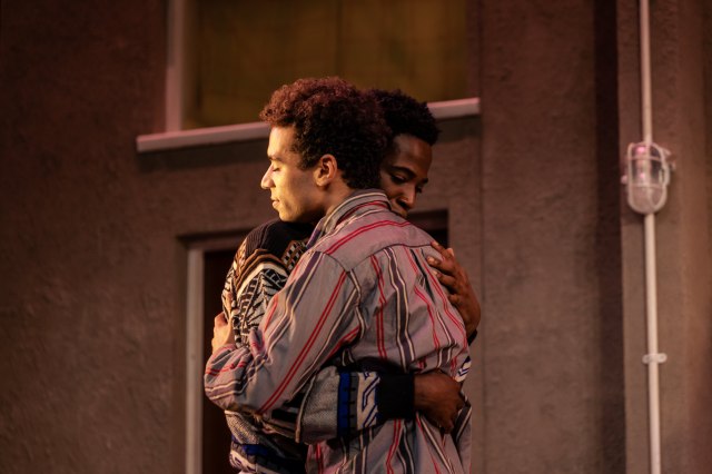 Rilwan Abiola Owokoniran (Jamie) and Raphael Akuwudike (Ste) in Beautiful Thing at Stratford East. Photographer The Other Richard. Actors Rilwan Abiola Owokoniran and Raphael Akuwudike embrace during a scene from Beautiful Thing