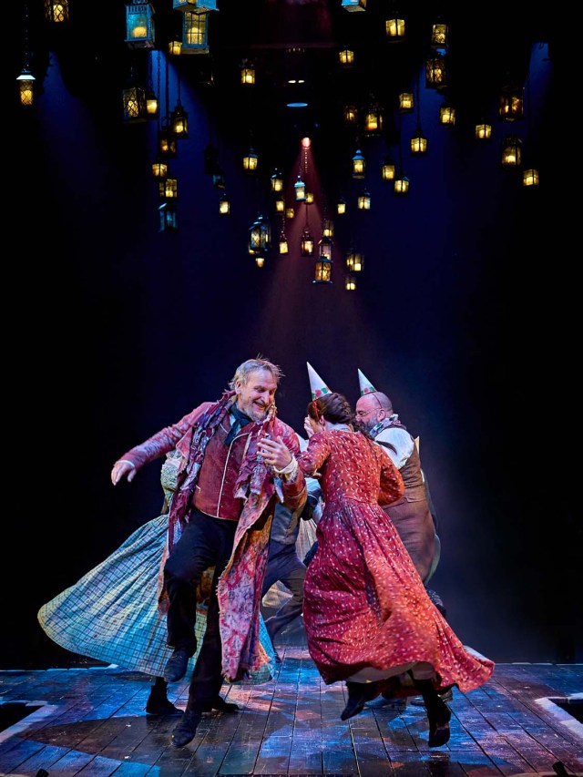 Christopher Eccleston as Ebenezer Scrooge, Frances McNamee as Belle and Alastair Parker as Fezziwig in A Christmas Carol at The Old Vic (2023), photo by Manuel Harlan Christopher Eccleston as Ebenezer Scrooge, Frances McNamee as Belle and Alastair Parker as Fezziwig in A Christmas Carol at The Old Vic (2023), photo by Manuel Harlan