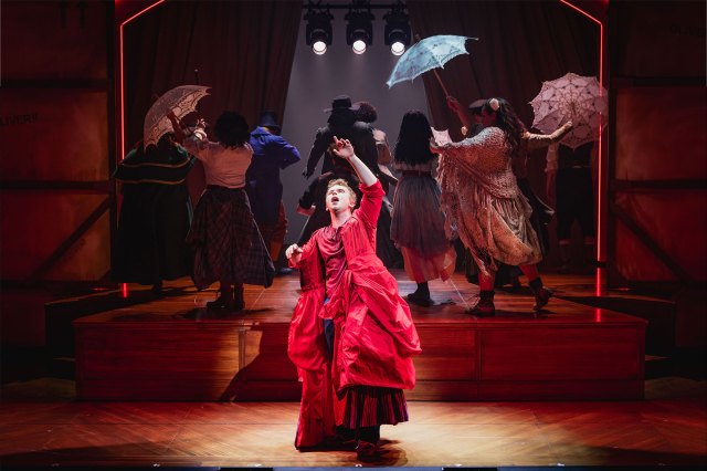 Joseph Peacock as David Starr playing Nancy in a red dress in a scene from Becoming Nancy at Birmingham Rep