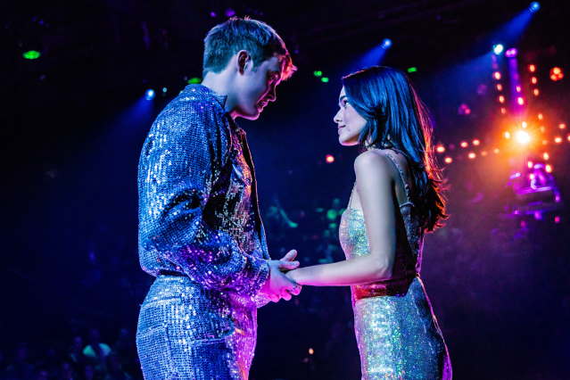 Kit Connor (Romeo) and Rachel Zegler (Juliet)in Romeo + Juliet, they hold hands at a party