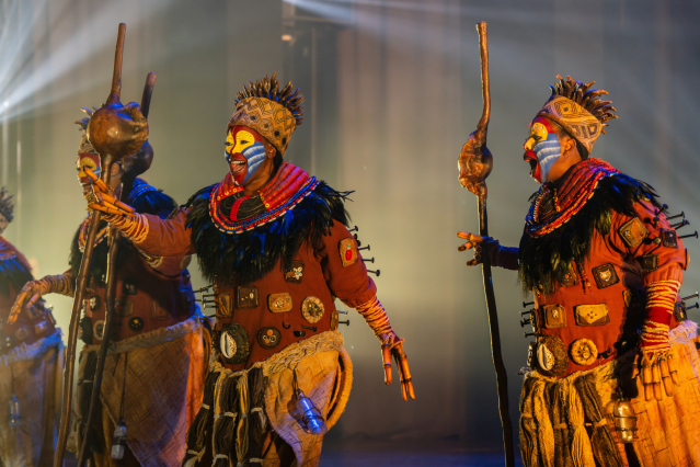 Three performers as Rafiki on stage