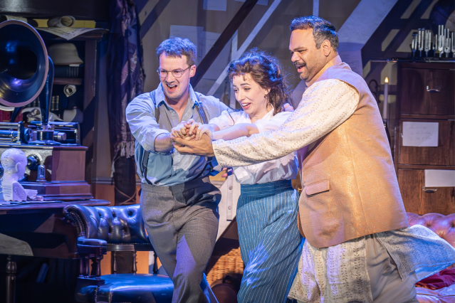 David Seadon-Young (Henry Higgins), Molly Lynch (Eliza Doolittle) and Minal Patel (Colonel Pickering) in My Fair Lady - the three hold in a ballroom position and dance through a study