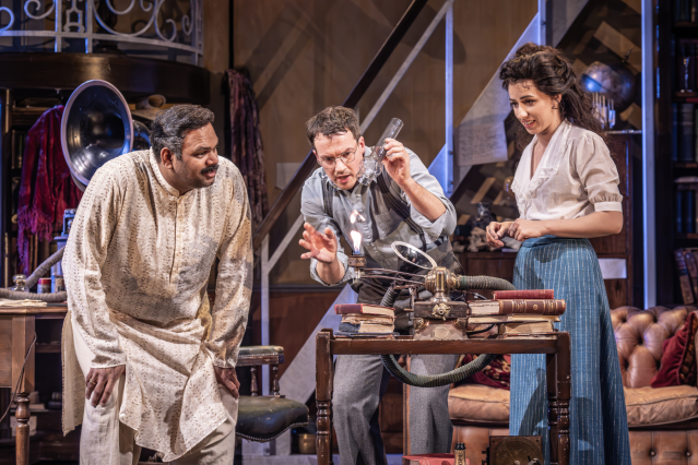 Minal Patel (Colonel Pickering), David Seadon-Young (Henry Higgins), Molly Lynch (Eliza Doolittle) in My Fair Lady, in a study they gather around a flame