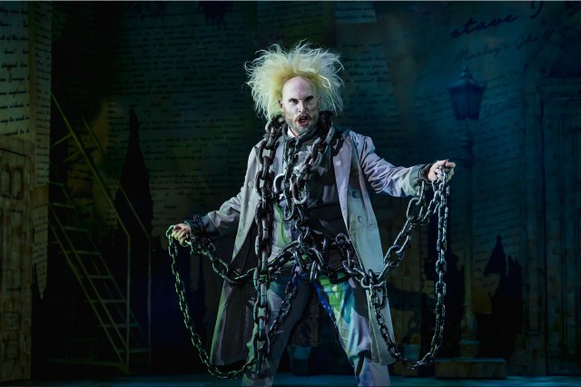 An actor on stage, dressed as a ghostly Jacob Marley in chains
