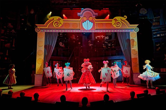 A group of dancers and actors in brightly coloured costumes on stage