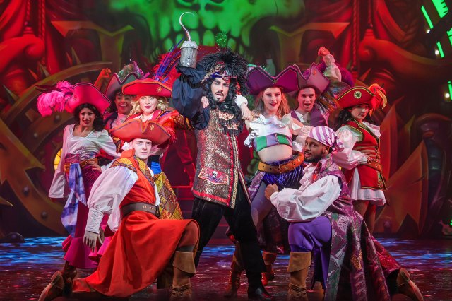 A group of actors dressed as pirates, one as Captain Hook, on stage in a pantomime