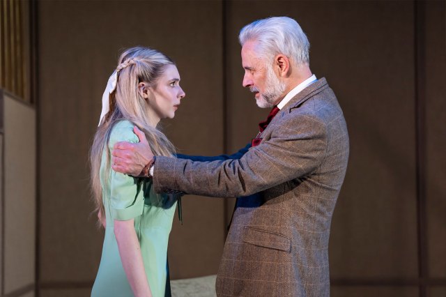 A younger actress in a green dress and an older actor in a suit on stage