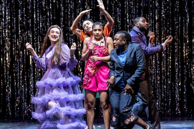 A group of actors dance in a party scene on stage