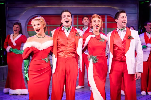 White Christmas 1 Two actors and two actresses in red, festive costumes on stage