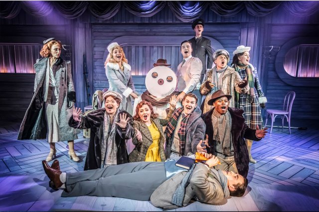 White Christmas 2 A group of actors in 1940s period costume surrounding a snowman on stage