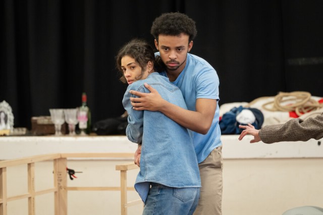 An actor and an actress embrace in a rehearsal room