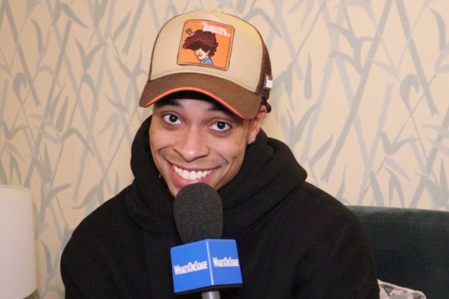 Actor Jamaal Fields-Green in a dressing room, holding a WhatsOnStage-branded microphone
