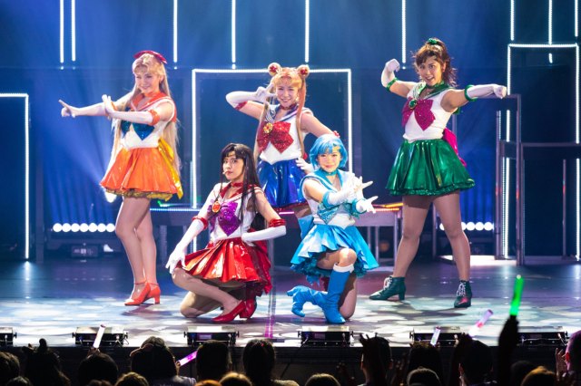 Five performers on stage dressed as characters from the Pretty Guardian Sailor Moon anime series