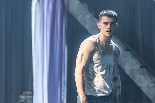 An actor stands on stage in a grubby white vest