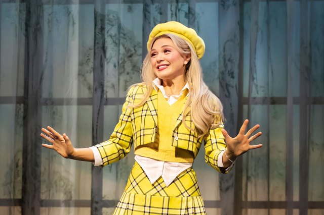 An actress on stage, wearing a yellow plaid outfit