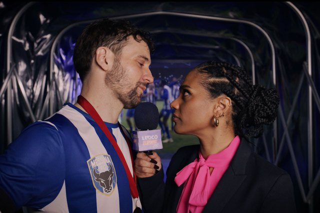 An actor posing as a football and an actress posing as a reporter with a microphone