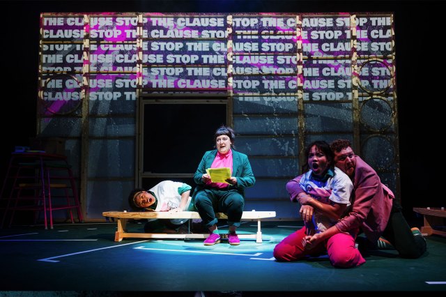Four actors gathered on stage in front of projections of the slogan "Stop the Cause"