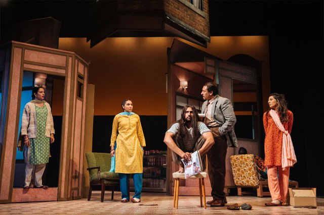 A group of five actors, three wearing south Asian costumes, gathered on a living room set on stage