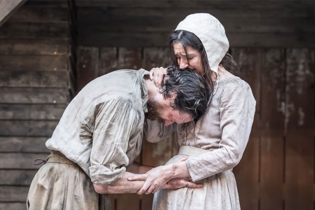 An actor and an actress in 17th-century period costumes console each other on stage