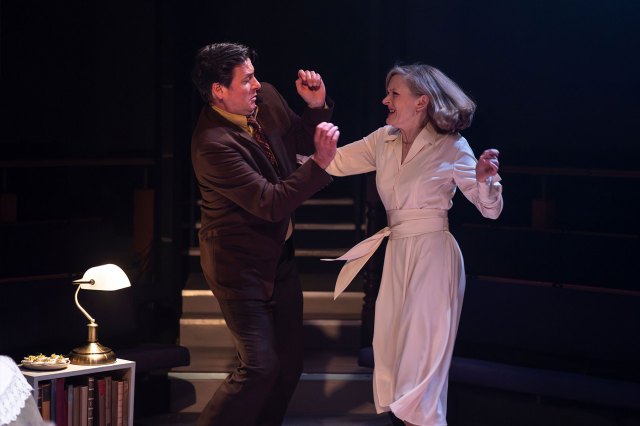 An actor and an actress, both smartly dressed, fighting on stage 