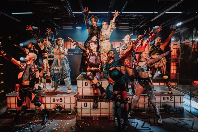 A group of actors in dystopian costumes in a nightclub setting