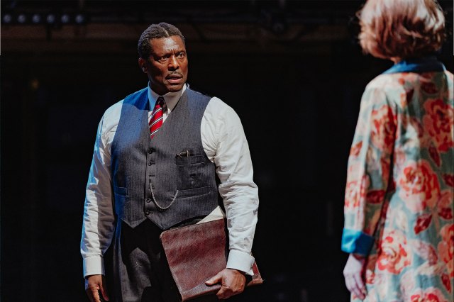An actor in a shirt, waistcoat and tie faces an actress on stage