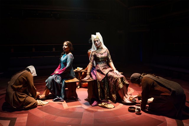 A group of actors gathered on stage in period costumes
