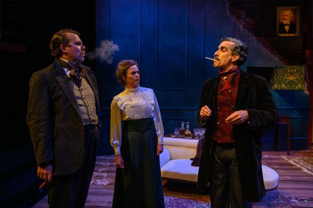 Three actors in period costumes, gathered on stage