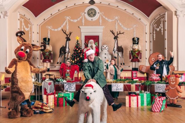 A Christmas Fair set up in a town hall - there are presents and tinsels and a man riding a polar bear!
