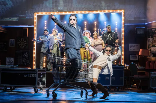 L R Sam Lupton as Dave, Hayley Tamaddon as Nicky & cast in BANK OF DAVE, credit Marc Brenner 2 L R Sam Lupton as Dave, Hayley Tamaddon as Nicky & cast in BANK OF DAVE, credit Marc Brenner 2